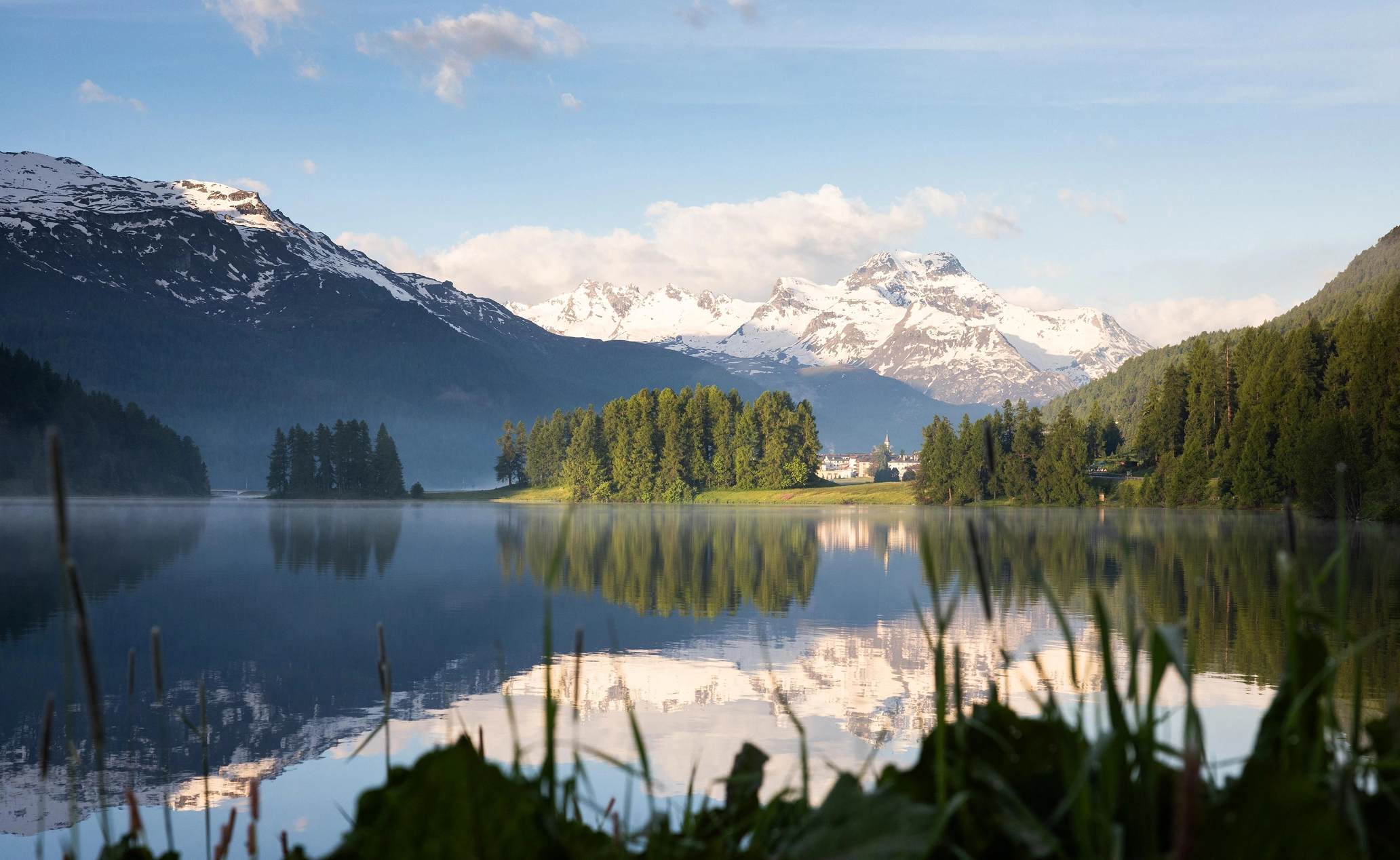 A picture of the Engadin valley with a lake on it.